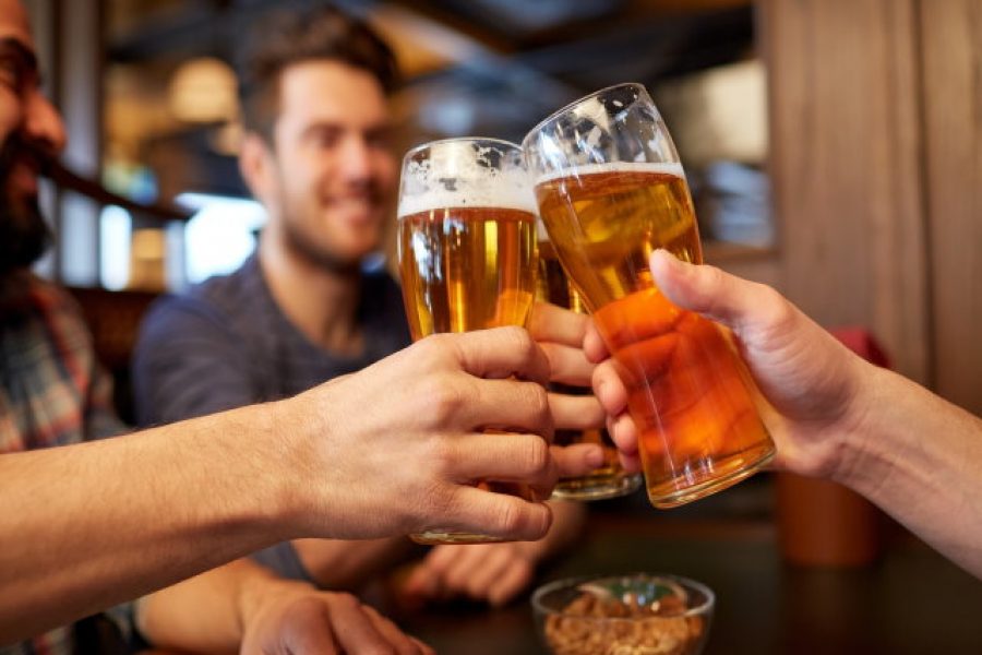 people, men, leisure, friendship and celebration concept - happy male friends drinking beer and clinking glasses at bar or pub
