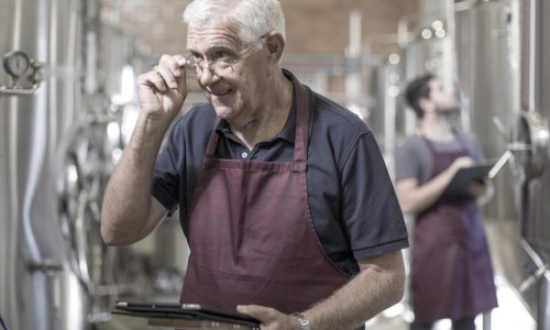 Brewers in brewery standing next to stainless steel tanks