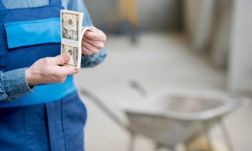 Builder counting his salary at the construction site. Close-up view focused on the money