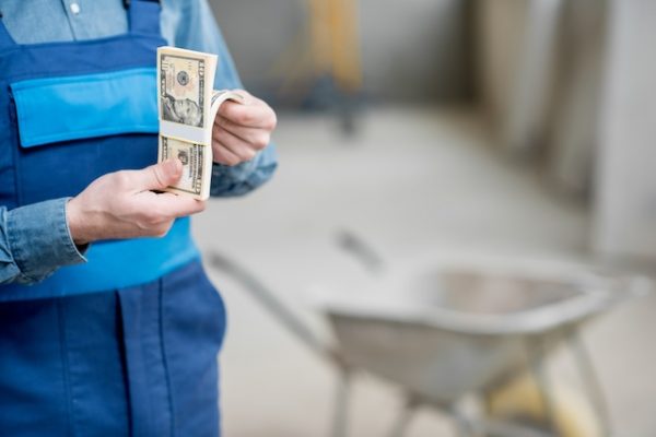 Builder counting his salary at the construction site. Close-up view focused on the money